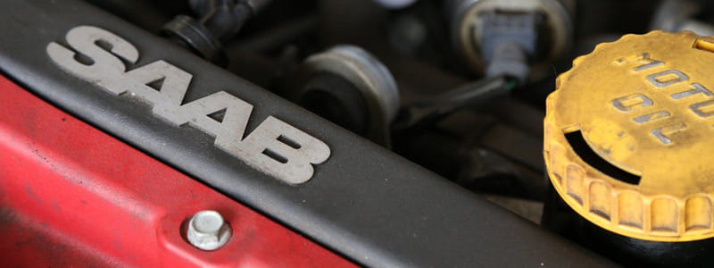 Saab-Schriftzug auf der Motorabdeckung eines roten Fahrzeugs neben dem Öleinfülldeckel